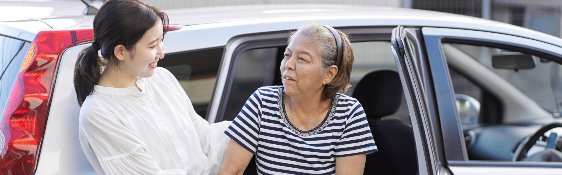 a woman helping elderly woman getting out of a vehicle